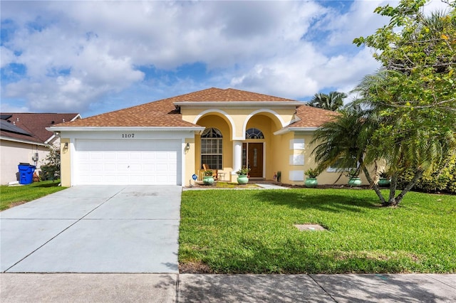 mediterranean / spanish-style house with a garage, a front yard, concrete driveway, and stucco siding