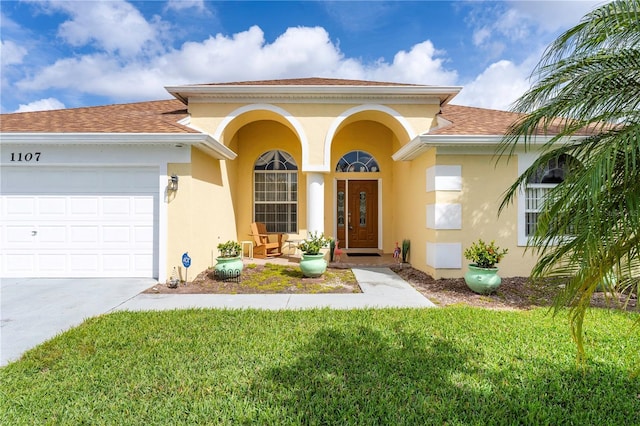 view of exterior entry with a garage, a shingled roof, a lawn, and stucco siding