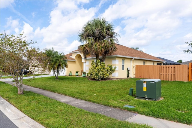 view of front of home with a front yard, fence, and stucco siding