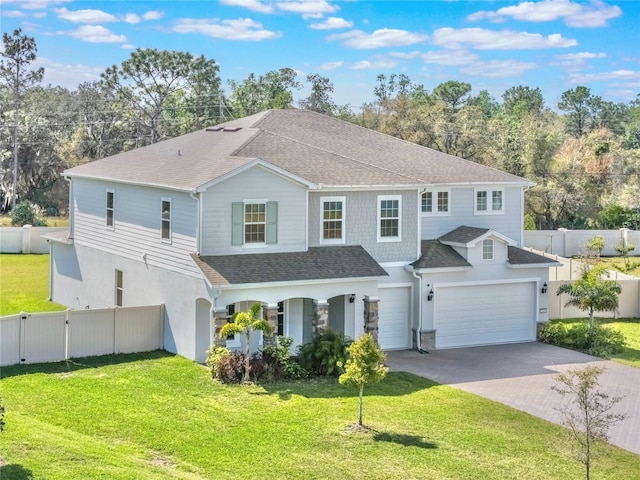 view of front of house with a shingled roof, decorative driveway, a front yard, and fence