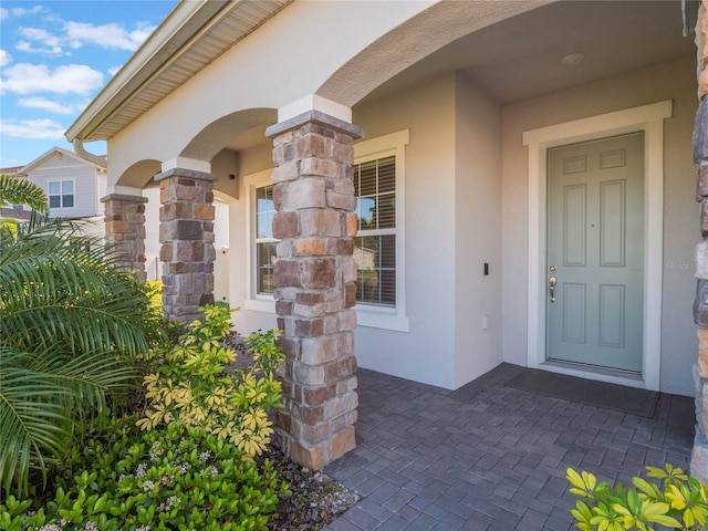 doorway to property with stone siding and stucco siding