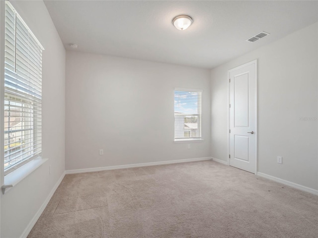 unfurnished room featuring baseboards, visible vents, and light carpet