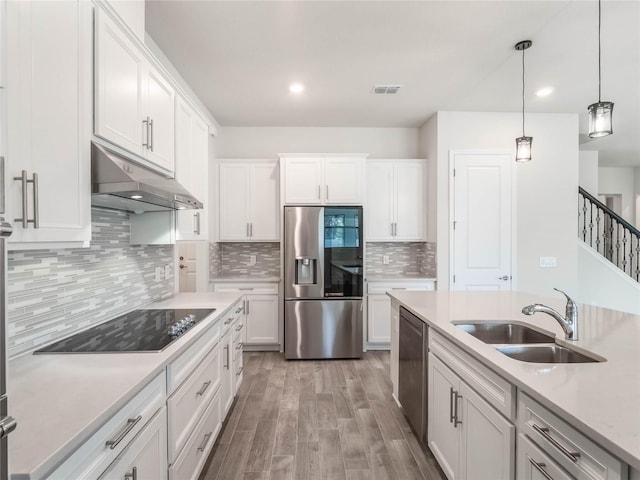 kitchen featuring under cabinet range hood, light countertops, appliances with stainless steel finishes, white cabinetry, and a sink