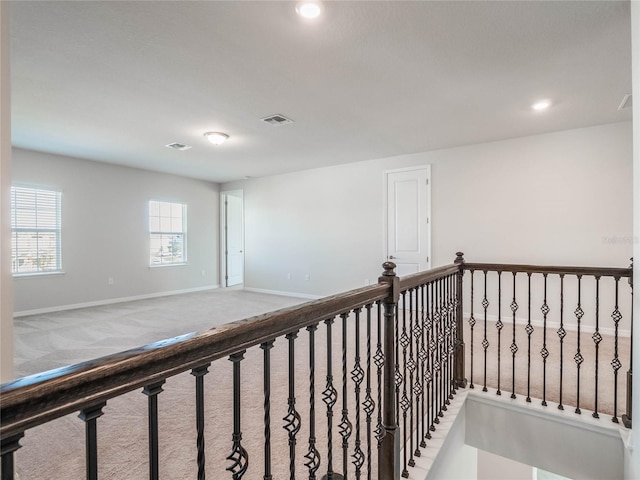 hallway featuring an upstairs landing, visible vents, carpet flooring, and baseboards