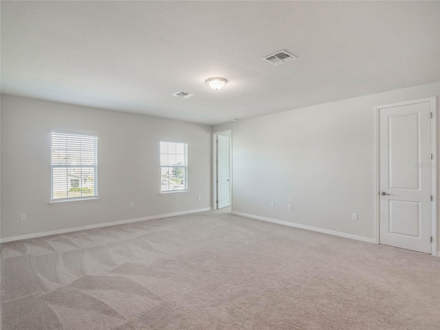 unfurnished room with light colored carpet, visible vents, and baseboards