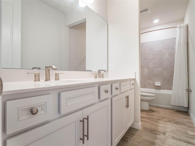 full bath featuring vanity, shower / bathtub combination with curtain, wood finished floors, visible vents, and toilet