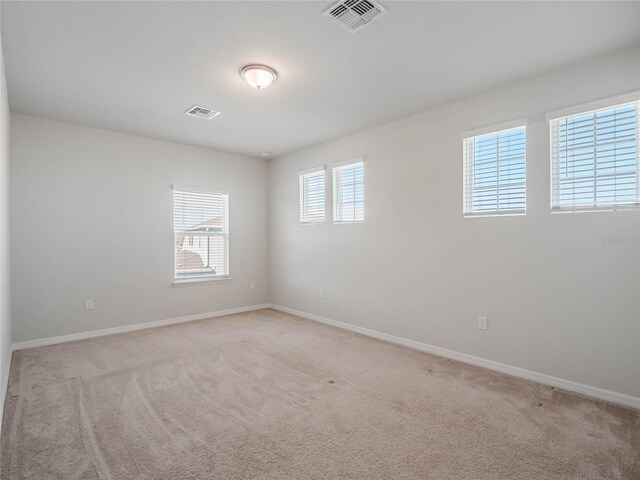 unfurnished room with visible vents, light carpet, and baseboards