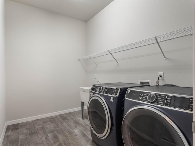 clothes washing area featuring washing machine and clothes dryer, laundry area, baseboards, and dark wood-style floors