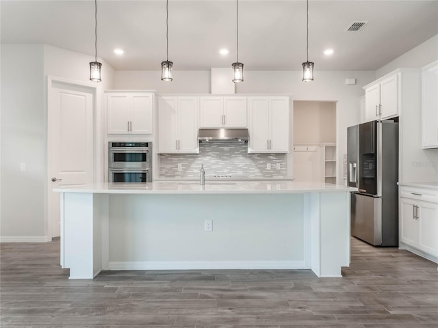 kitchen with under cabinet range hood, stainless steel appliances, backsplash, and light countertops