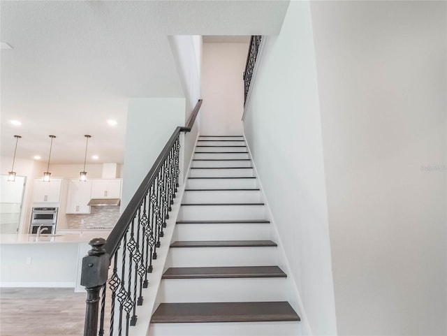 stairs with recessed lighting and wood finished floors