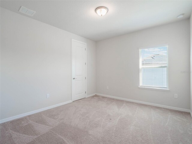 unfurnished room featuring light carpet, visible vents, and baseboards