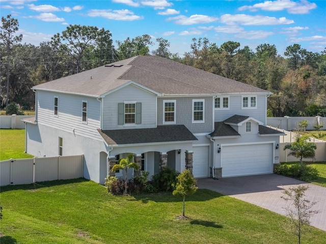 view of front of house featuring fence, roof with shingles, an attached garage, a front lawn, and decorative driveway