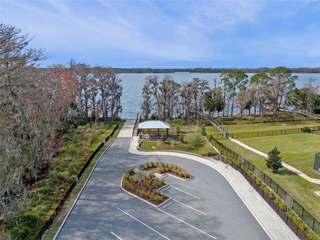 surrounding community featuring a water view, uncovered parking, and fence