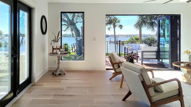 living area featuring baseboards, a water view, a healthy amount of sunlight, and wood finished floors