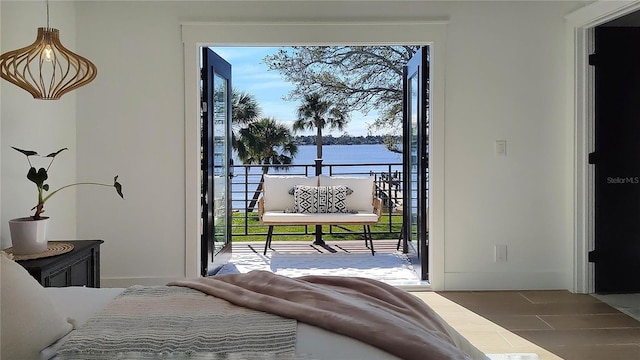 bedroom with baseboards, multiple windows, access to exterior, and a water view