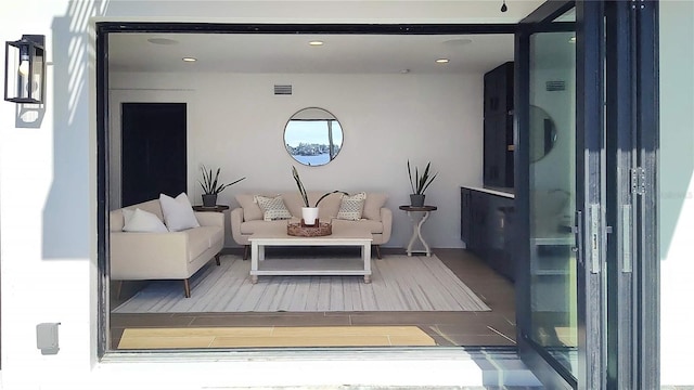 living room with recessed lighting, wood finished floors, and visible vents