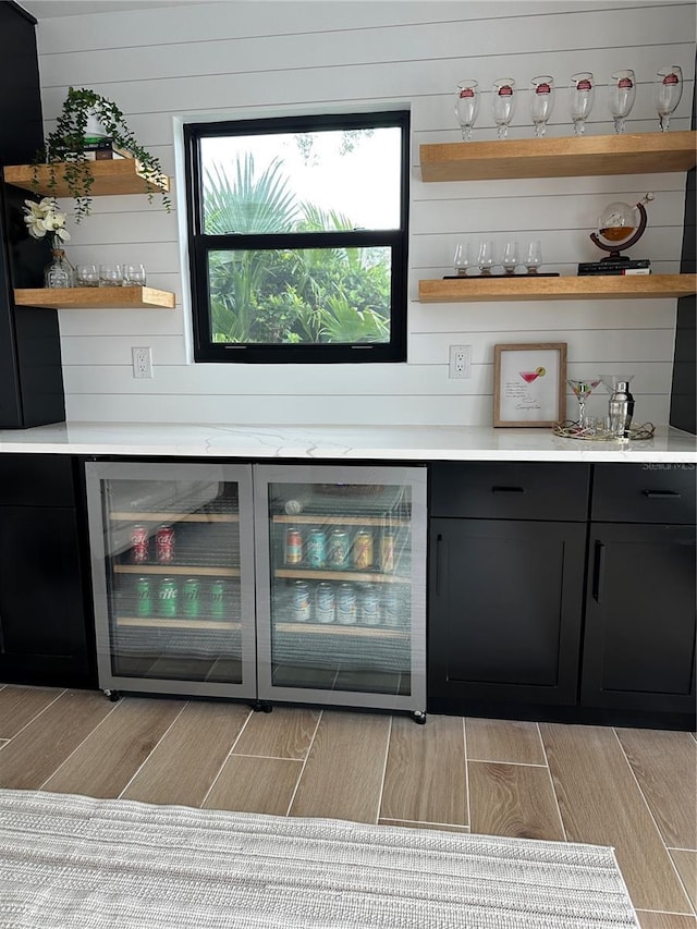 bar with wine cooler, a bar, and wood tiled floor