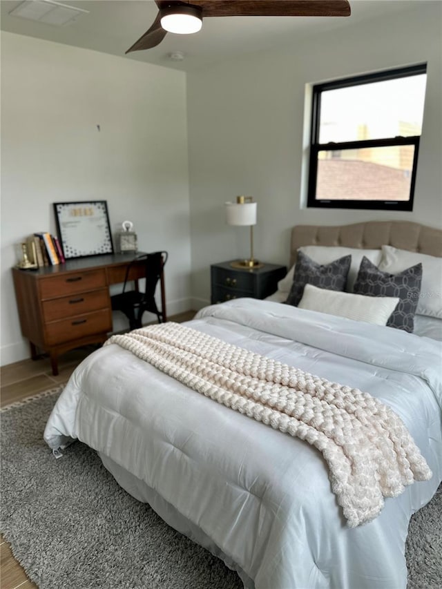 bedroom with visible vents, baseboards, wood finished floors, and a ceiling fan