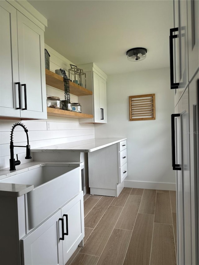 kitchen featuring a sink, open shelves, white cabinets, light countertops, and wood tiled floor