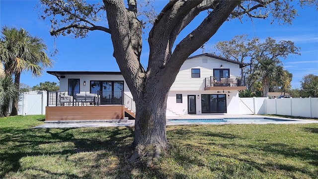 rear view of house featuring a yard, a fenced backyard, a balcony, an outdoor pool, and a gate