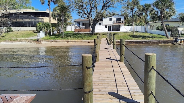 dock area with a lawn, fence, and a water view