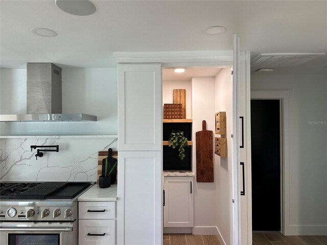 kitchen featuring light countertops, high end stainless steel range, white cabinetry, wall chimney range hood, and tasteful backsplash