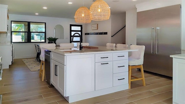 kitchen with wood tiled floor, recessed lighting, a sink, light countertops, and white cabinetry