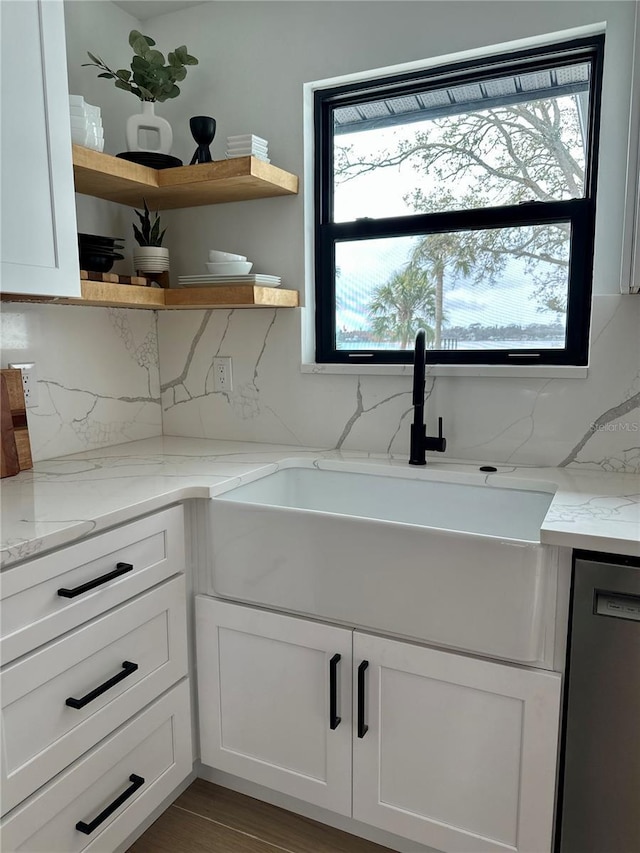 interior space with dishwasher, tasteful backsplash, white cabinetry, and a sink