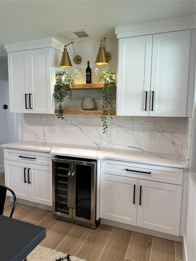 bar with beverage cooler, visible vents, backsplash, and wood tiled floor