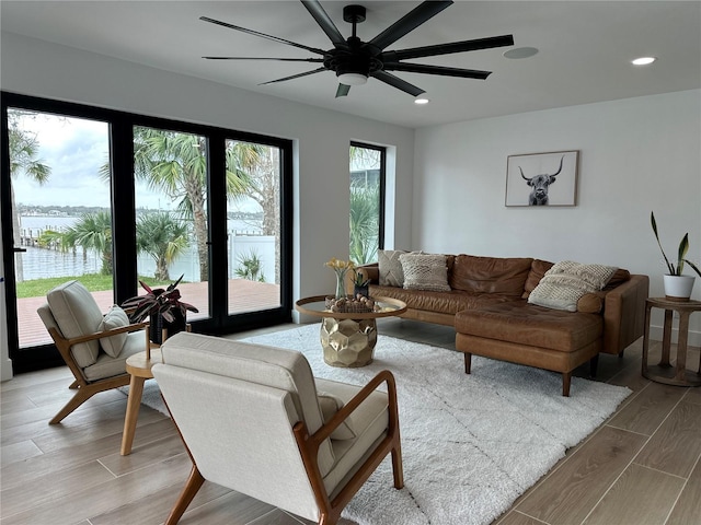 living room with wood finish floors, a water view, ceiling fan, and recessed lighting