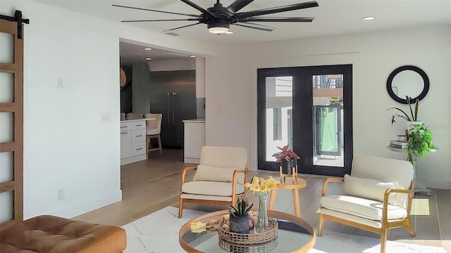 living area featuring visible vents, ceiling fan, a barn door, recessed lighting, and wood finished floors