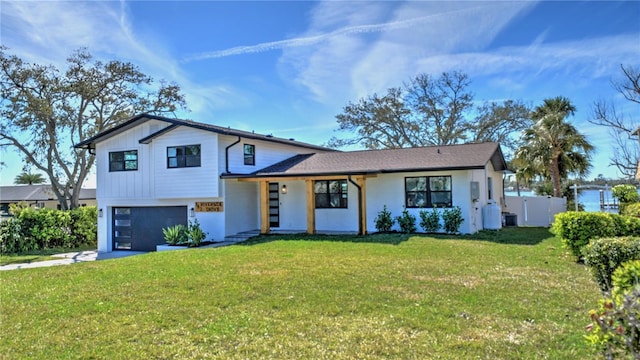 split level home with a garage, concrete driveway, a front yard, and fence