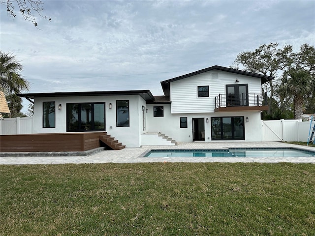 back of house featuring a patio, fence, a yard, a fenced in pool, and a balcony