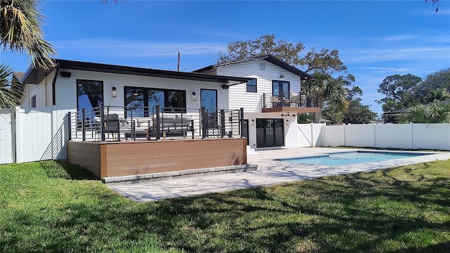 rear view of property featuring a patio, a fenced in pool, a fenced backyard, stucco siding, and a lawn