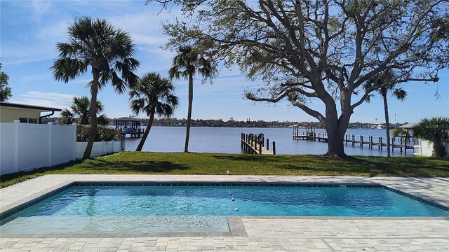 outdoor pool featuring a dock, fence, a water view, and a lawn