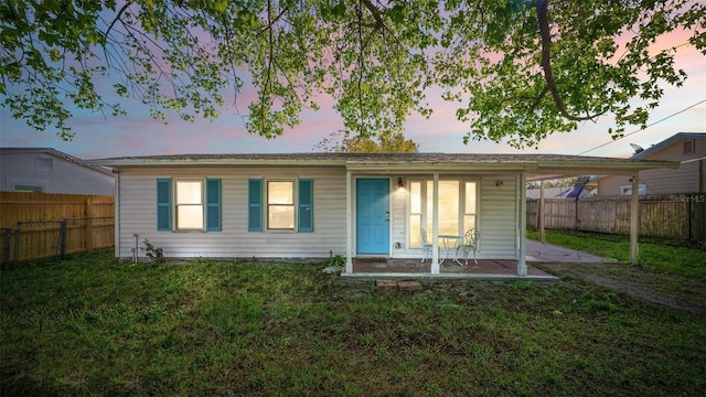 back of house featuring a yard, a carport, and a fenced backyard