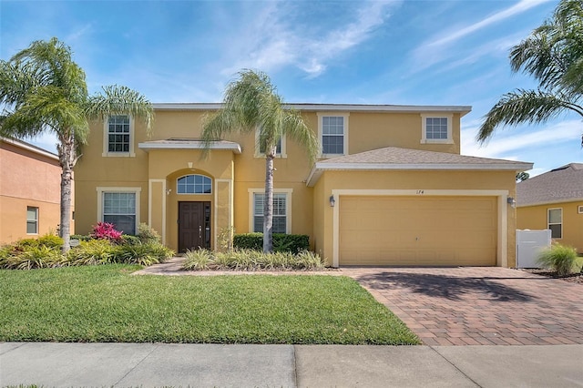 view of front of home with a front lawn, decorative driveway, an attached garage, and stucco siding