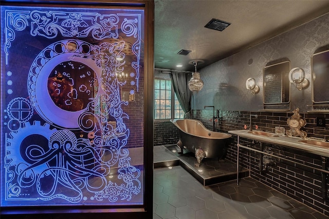 full bathroom featuring a freestanding tub, visible vents, a textured ceiling, and tile patterned floors