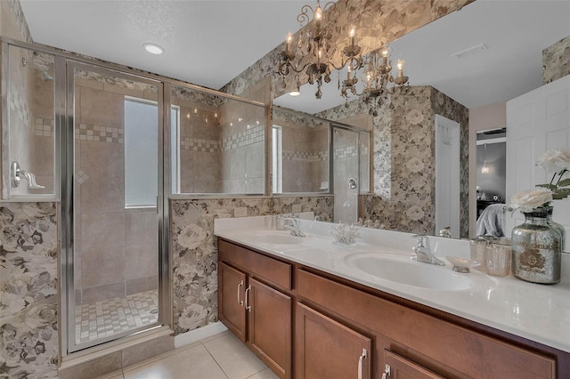 bathroom featuring double vanity, a stall shower, a sink, and tile patterned floors