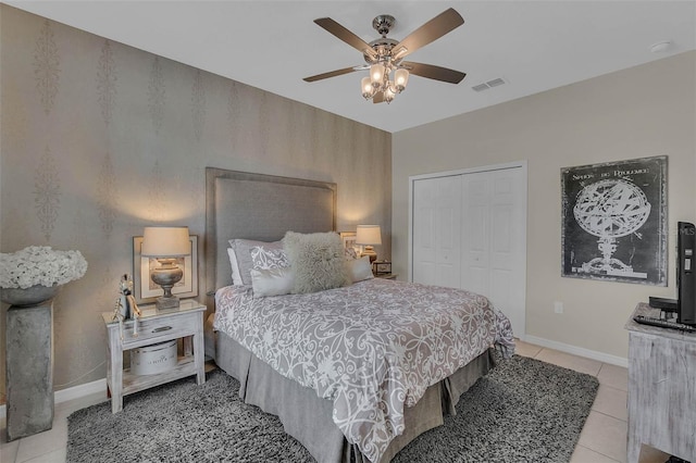 bedroom with baseboards, visible vents, a ceiling fan, a closet, and light tile patterned flooring