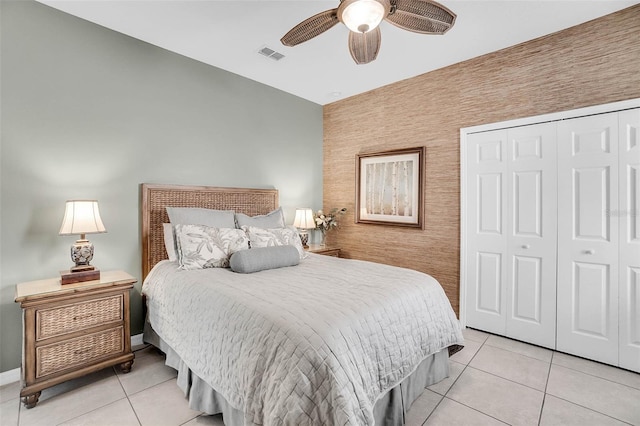 bedroom featuring light tile patterned floors, an accent wall, a closet, and visible vents