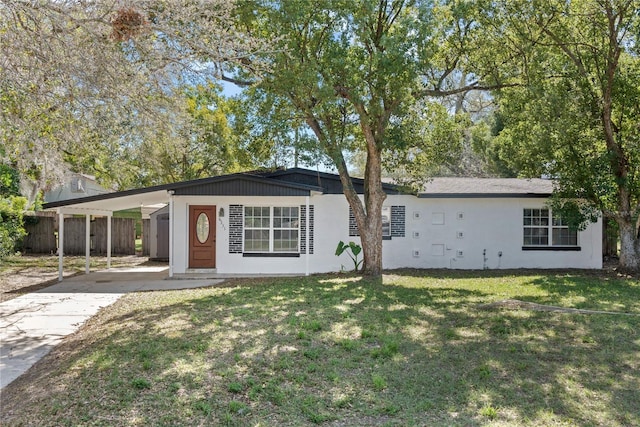 ranch-style house featuring driveway, fence, a carport, and a front yard