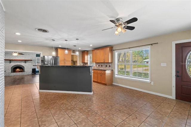 kitchen featuring freestanding refrigerator, a brick fireplace, light tile patterned flooring, and backsplash