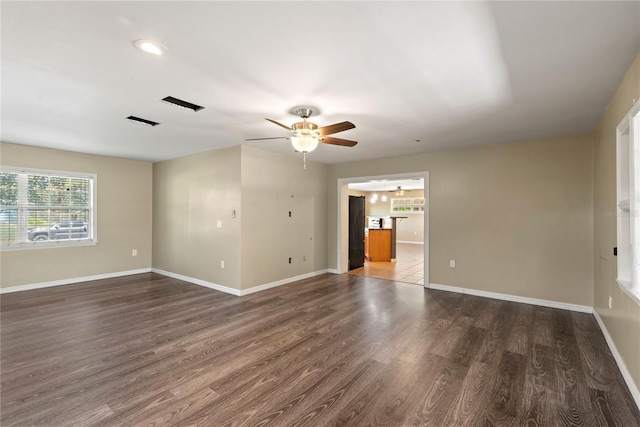 unfurnished room with a ceiling fan, visible vents, baseboards, and wood finished floors