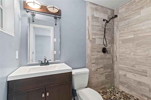 bathroom featuring tiled shower, vanity, and toilet