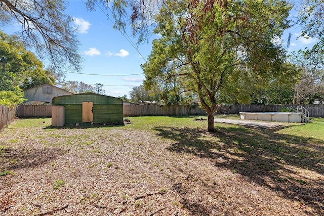 view of yard featuring a fenced in pool, an outbuilding, a fenced backyard, and a shed