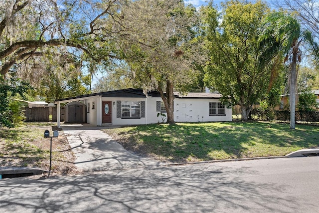 single story home featuring a carport, a front yard, fence, and a shed