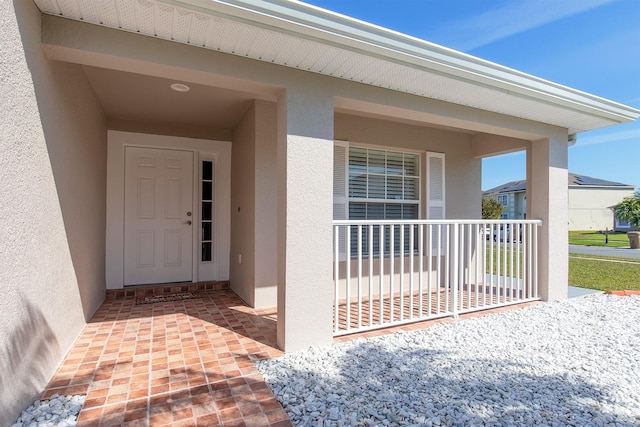 property entrance featuring covered porch and stucco siding