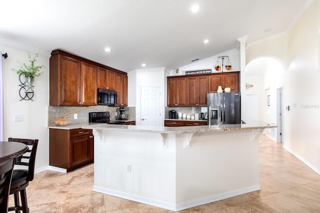 kitchen featuring black appliances, arched walkways, a breakfast bar, and decorative backsplash