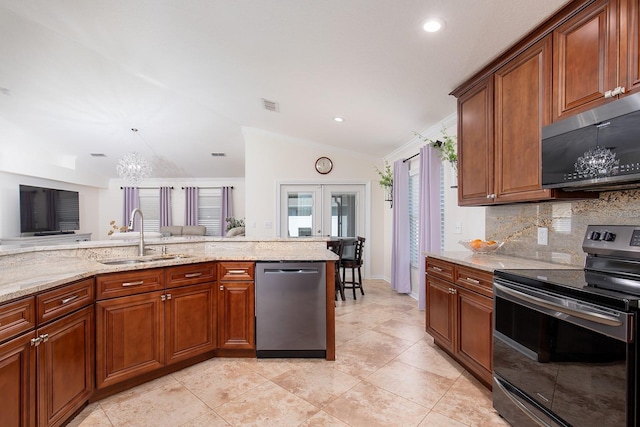 kitchen with brown cabinetry, lofted ceiling, appliances with stainless steel finishes, light stone countertops, and a sink